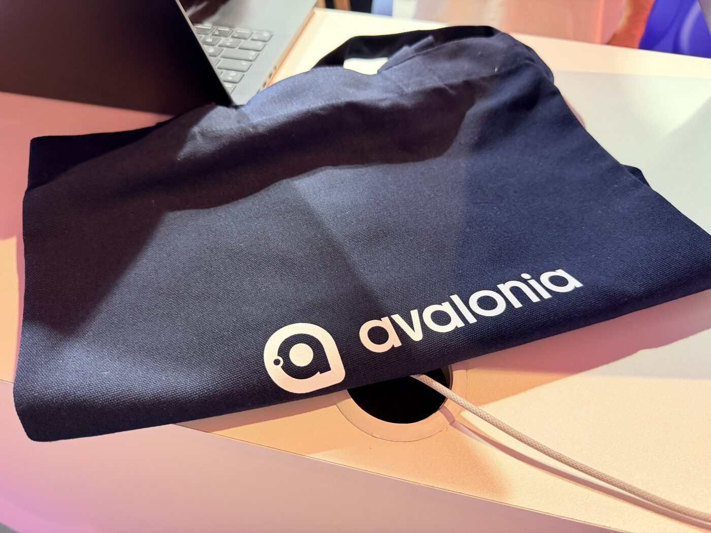 A navy Avalonia tote bag on a booth table next to a laptop
