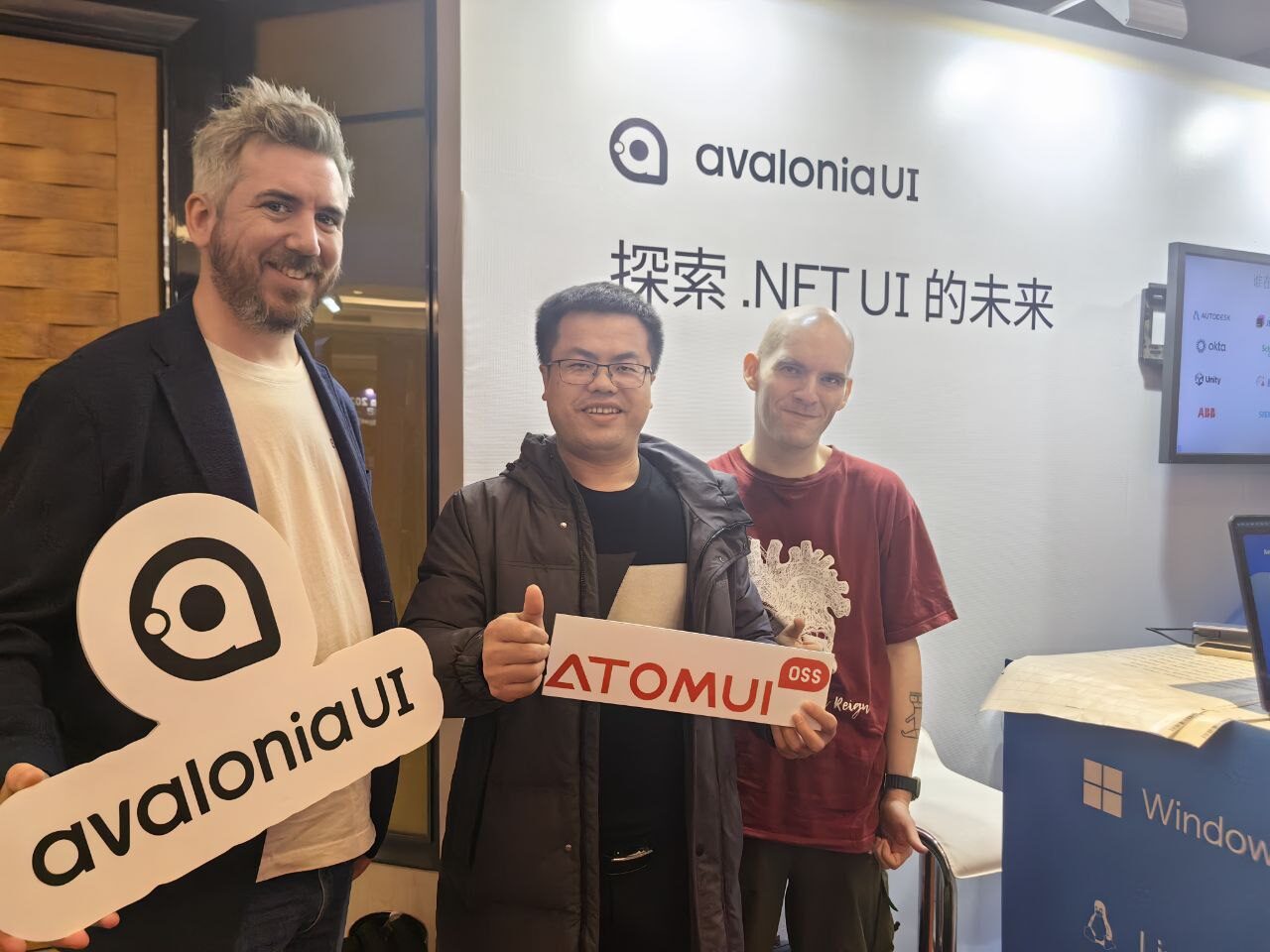 Avalonia team and community members holding Avalonia UI and AtomUI signs at a conference booth