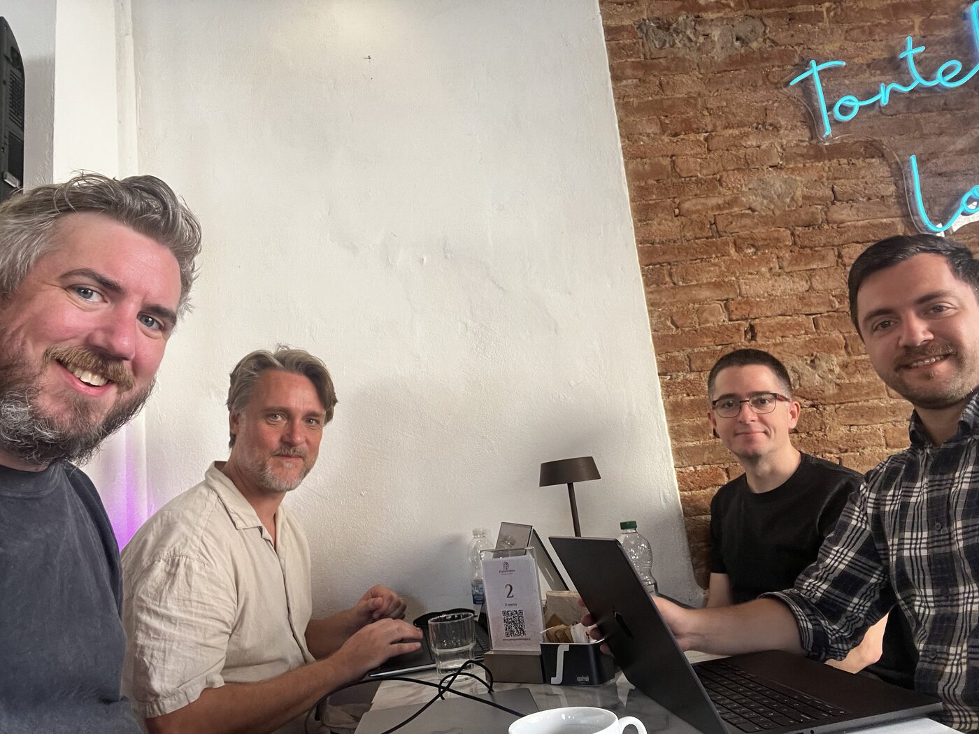 Four colleagues working on laptops around a cafe table