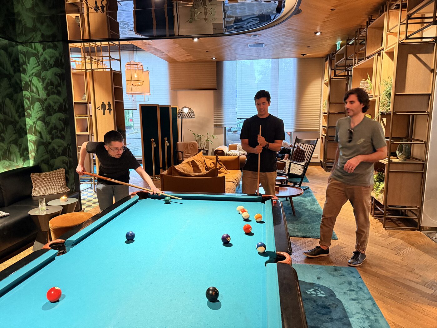 Three colleagues playing pool in a hotel lounge