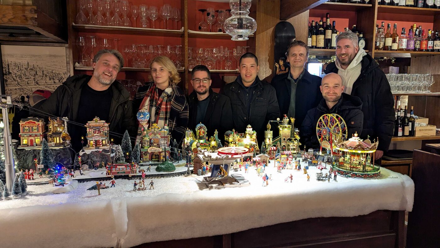 Seven members of the Avalonia team together behind a model Christmas village in a bar